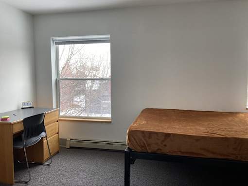 a bedroom with a bed and a desk and a window